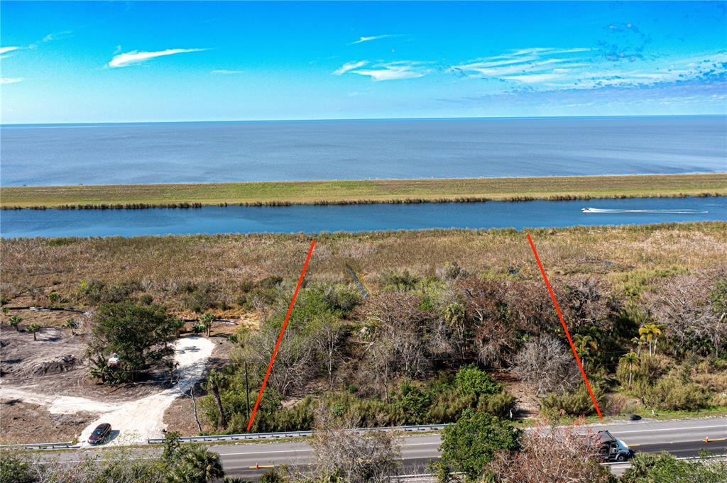 An aerial view shows a vacant lot bordering a canal with a levee and water — 15460 SW CONNERS HIGHWAY, OKEECHOBEE, FL