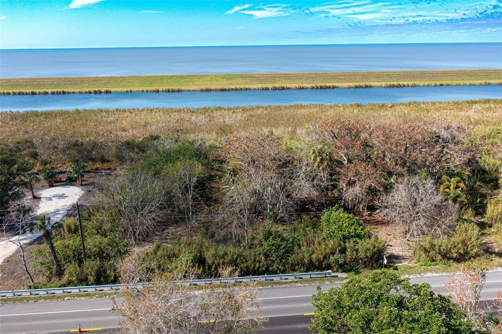 An aerial view shows a wooded lot situated between a road and a coastal waterway — 15460 SW CONNERS HIGHWAY, OKEECHOBEE, FL