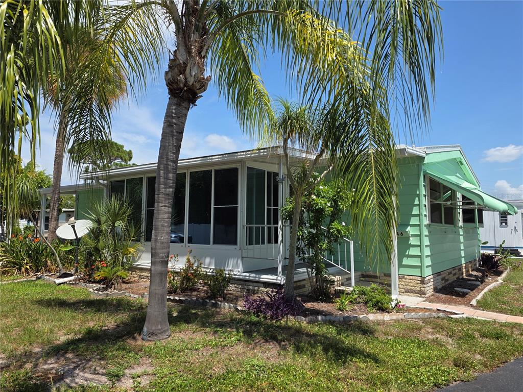 A light green mobile home features a screened-in porch and a palm tree in the yard — 1800 ENGLEWOOD ROAD UNIT 146, ENGLEWOOD, FL
