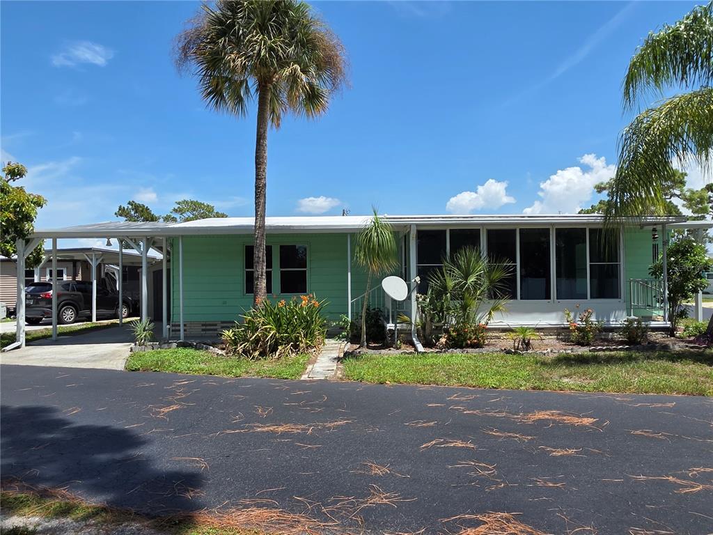 A light green manufactured home features a carport, a screened-in porch, and palm trees — 1800 ENGLEWOOD ROAD UNIT 146, ENGLEWOOD, FL