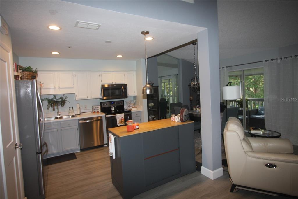 A kitchen with white cabinets, stainless steel appliances, and a dark gray island with wood countertop — 810 LOCH CALDER UNIT 25, APOPKA, FL