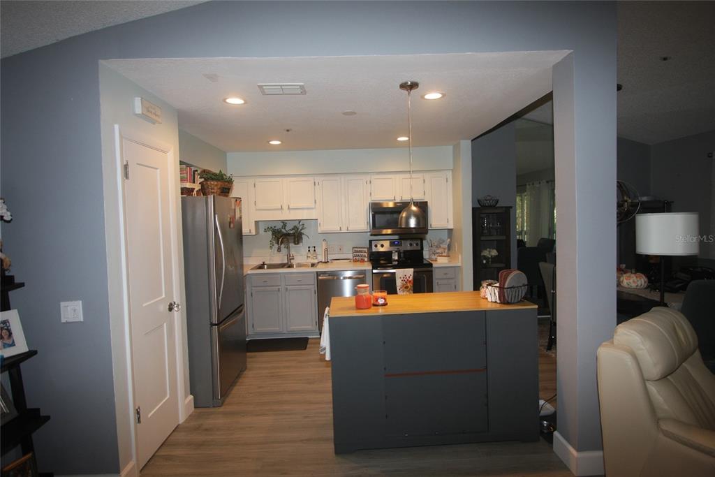 A kitchen features white upper cabinets, gray lower cabinets, stainless steel appliances, and a dark island — 810 LOCH CALDER UNIT 25, APOPKA, FL