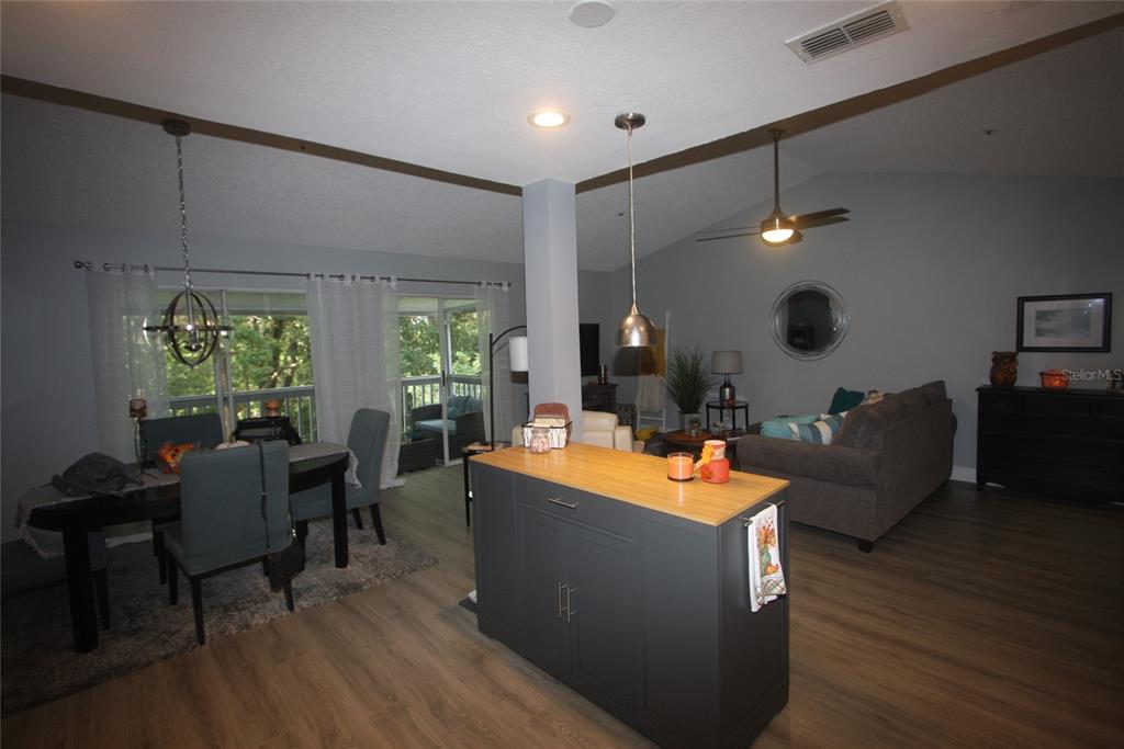 An open-concept living and dining area features a central kitchen island and sliding glass doors — 810 LOCH CALDER UNIT 25, APOPKA, FL