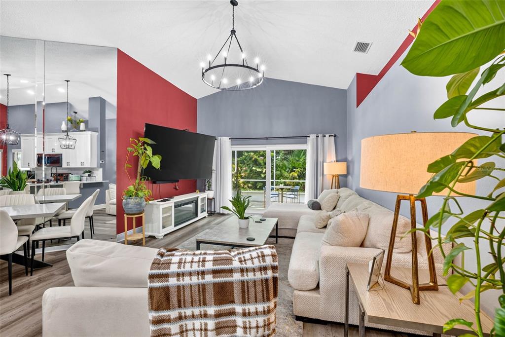 A living room features a vaulted ceiling, a red accent wall, and a large sectional sofa — 1721 SPLIT FORK DRIVE, OLDSMAR, FL