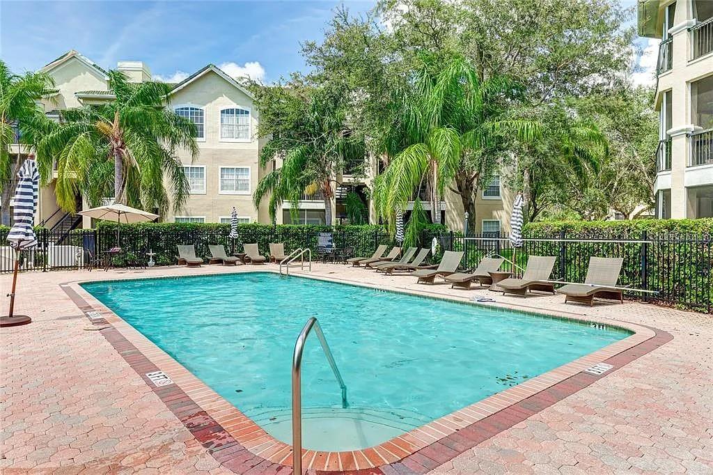 A rectangular swimming pool is surrounded by lounge chairs and palm trees at an apartment complex — 5110 NORTHRIDGE ROAD UNIT 208, SARASOTA, FL