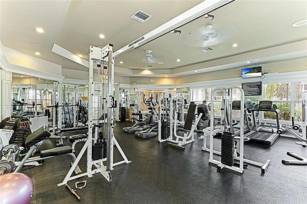 A fitness center features various weight machines, treadmills, and exercise equipment on a black floor — 5110 NORTHRIDGE ROAD UNIT 208, SARASOTA, FL