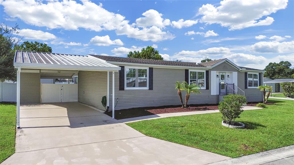 A single-story house with gray siding, a metal carport, and a concrete driveway — 490 LINDSEY DR, LAKELAND, FL