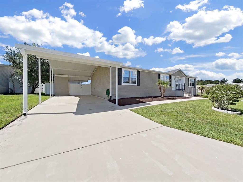 A light-gray single-story house features a concrete driveway, a carport, and a manicured lawn — 490 LINDSEY DR, LAKELAND, FL