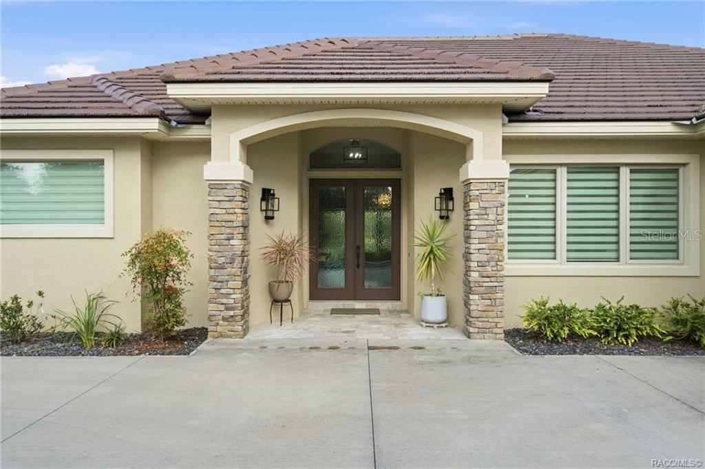 The exterior of a house features a stone-columned entryway with double doors and tiled roof — 2788 N CROSSWATER PATH, LECANTO, FL