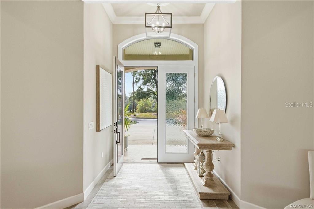 An entryway features a light-colored brick floor, a console table, and a glass-paneled front door — 2788 N CROSSWATER PATH, LECANTO, FL
