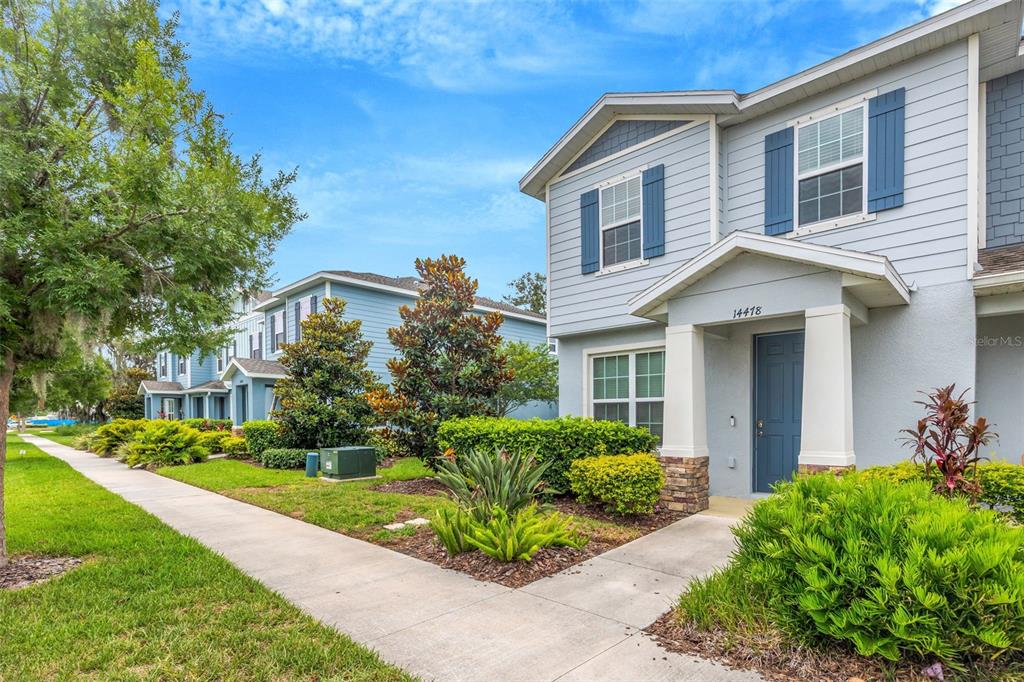 A two-story light blue townhouse with blue shutters and a covered front entryway — 14478 PROMENADE, ODESSA, FL