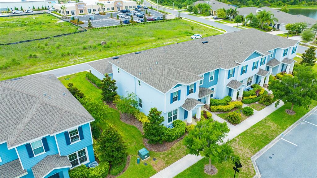 An aerial view shows a light blue multi-unit townhouse building with gray shingled roofs — 14478 PROMENADE, ODESSA, FL
