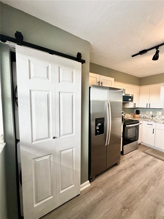 A kitchen features white cabinets, stainless steel appliances, and a sliding barn door — 800 COVE CAY DRIVE UNIT 4F, CLEARWATER, FL