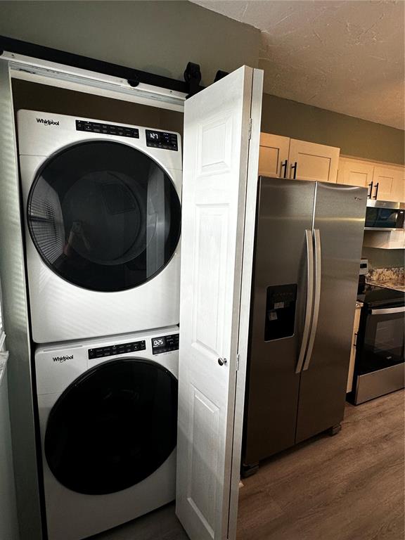 A kitchen features a stacked Whirlpool washer and dryer unit next to a stainless refrigerator — 800 COVE CAY DRIVE UNIT 4F, CLEARWATER, FL