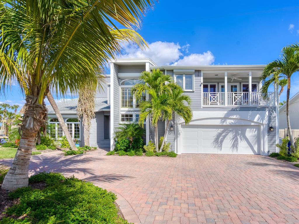 A two-story gray house with a white garage, a balcony, and a brick paver driveway — 3240 CASEY KEY ROAD, NOKOMIS, FL