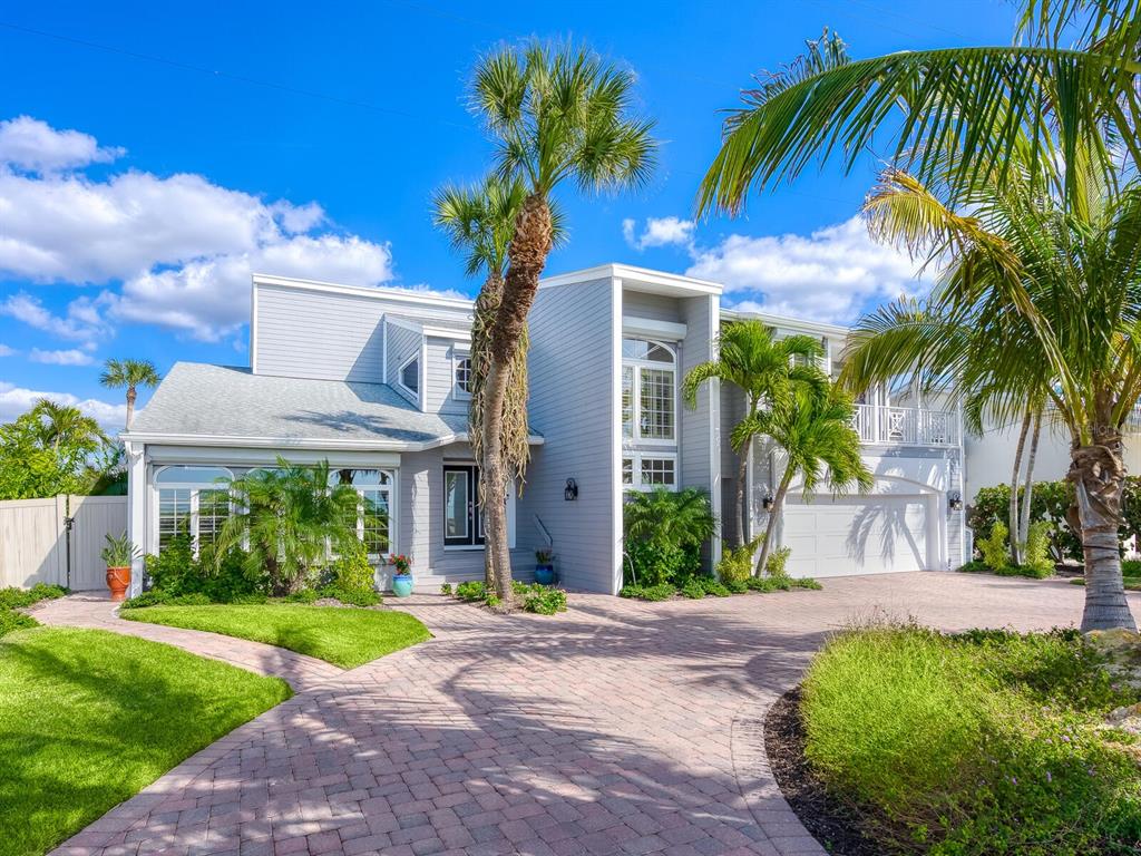 A two-story gray house with a brick driveway, palm trees, and a white garage — 3240 CASEY KEY ROAD, NOKOMIS, FL