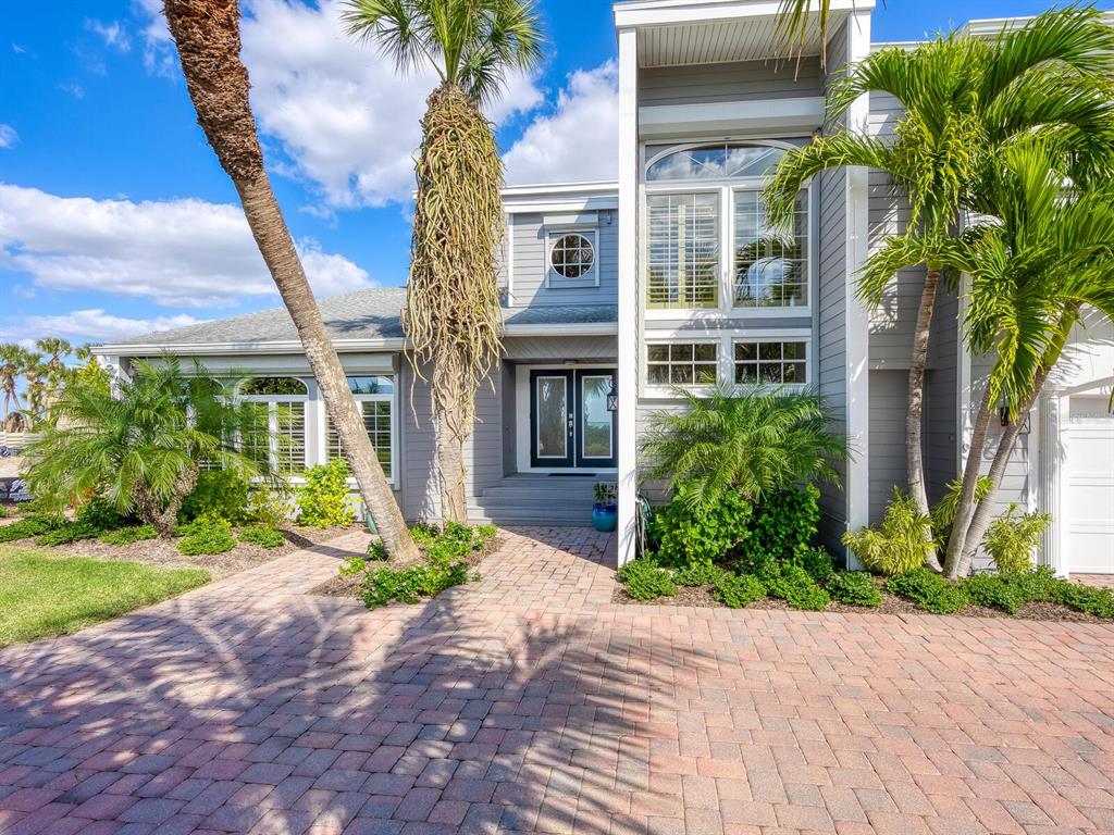 A gray two-story house with a brick paver driveway and palm trees in the front yard — 3240 CASEY KEY ROAD, NOKOMIS, FL