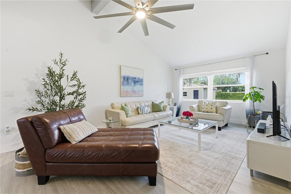 A bright living room features light wood-look flooring, a vaulted ceiling, and a sliding glass door — 1389 PONCE DE LEON BOULEVARD, WINTER SPRINGS, FL