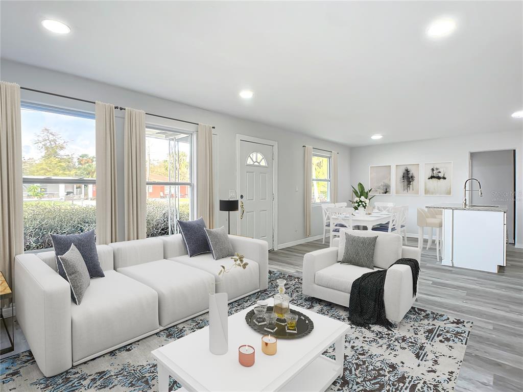 A living room with a white sofa, armchair, and dining area on light wood flooring — 933 MARION STREET, DAYTONA BEACH, FL