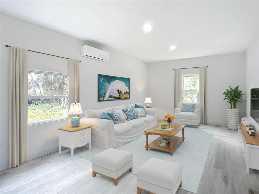 This living room features light wood-look flooring, a white sofa, two ottomans, and a coffee table — 933 MARION STREET, DAYTONA BEACH, FL