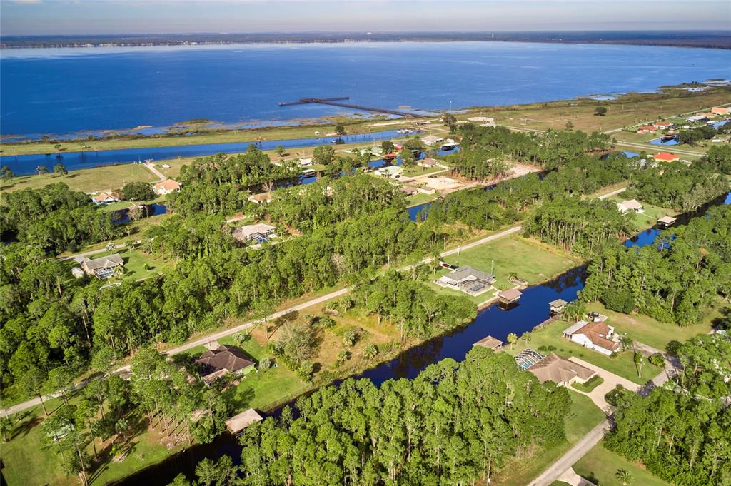 An aerial view shows houses nestled among trees along a canal leading to a lake — 1024 CALLIANDRA DRIVE, INDIAN LAKE ESTATES, FL