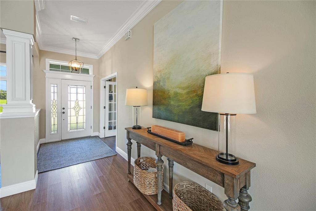 An entryway features a wooden console table, two lamps, and a large abstract painting — 10757 COUNTY ROAD 223, OXFORD, FL