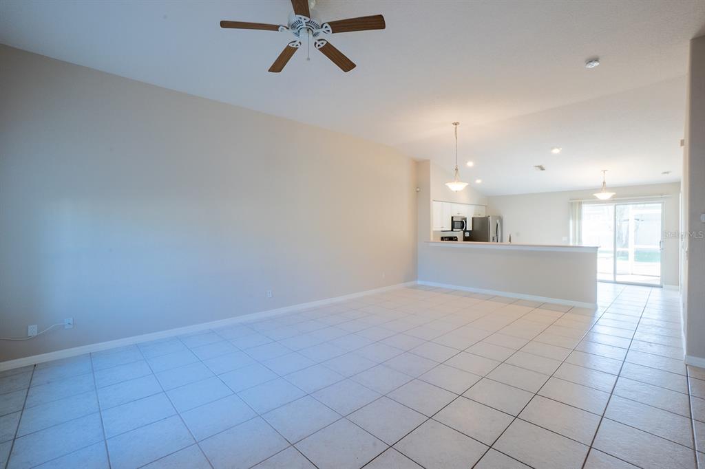 An open-concept living area with tiled floors, a ceiling fan, and a kitchen breakfast bar — 13 BUTTONWOOD LANE, PALM COAST, FL