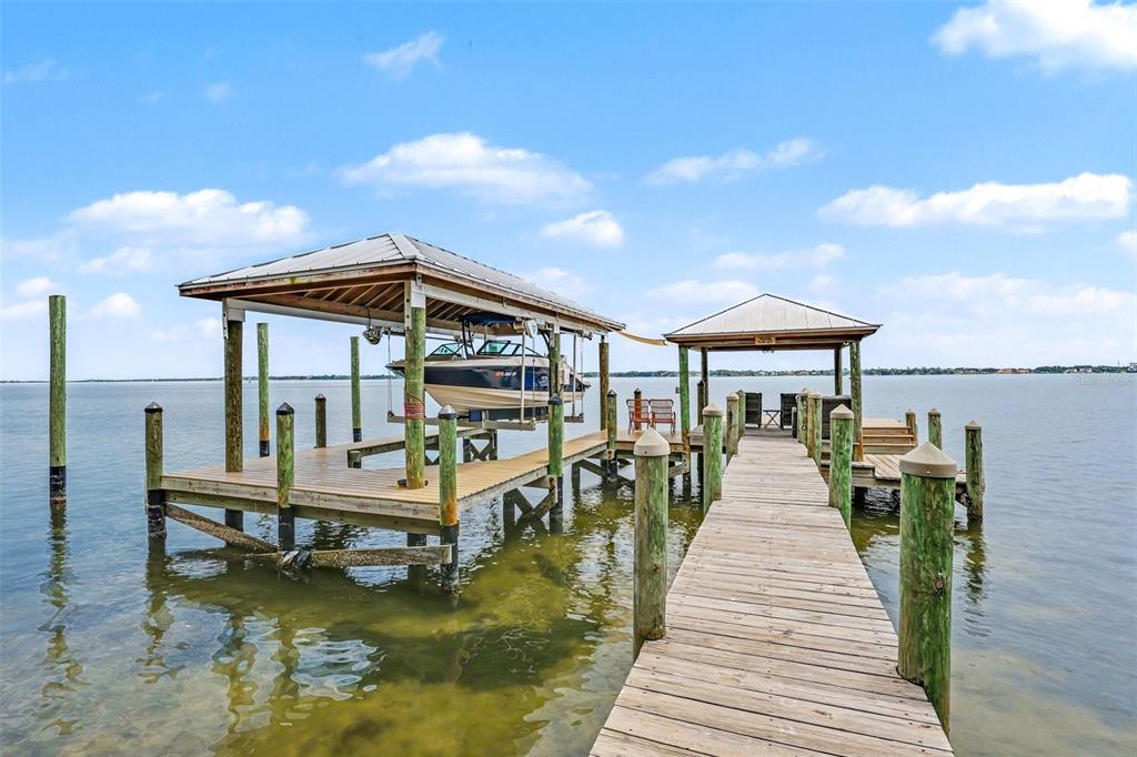 A wooden dock extends into the water, featuring a covered boat lift and seating area — 7 MITCHELL STREET, COCOA, FL