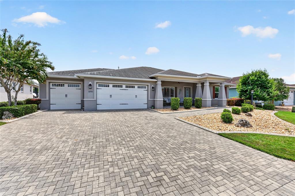 A single-story house with a paved driveway, three-car garage, and a covered front porch — 8745 SW 94TH AVENUE, OCALA, FL