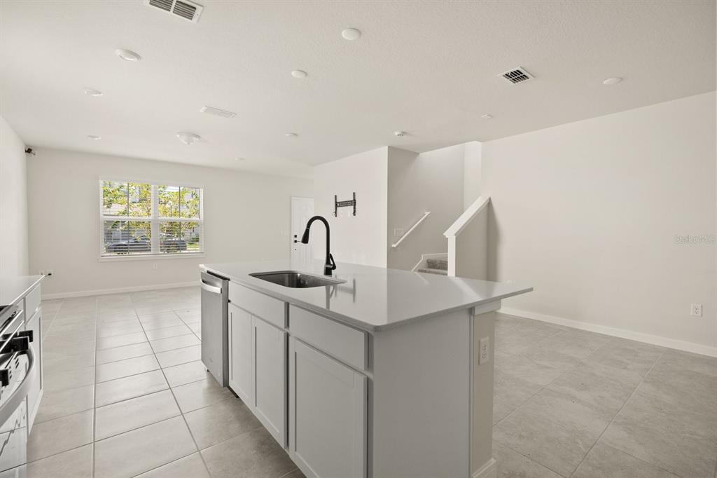 A kitchen island with a sink and faucet sits in a room with tiled floors — 4066 FEATHER TREE DRIVE, APOPKA, FL