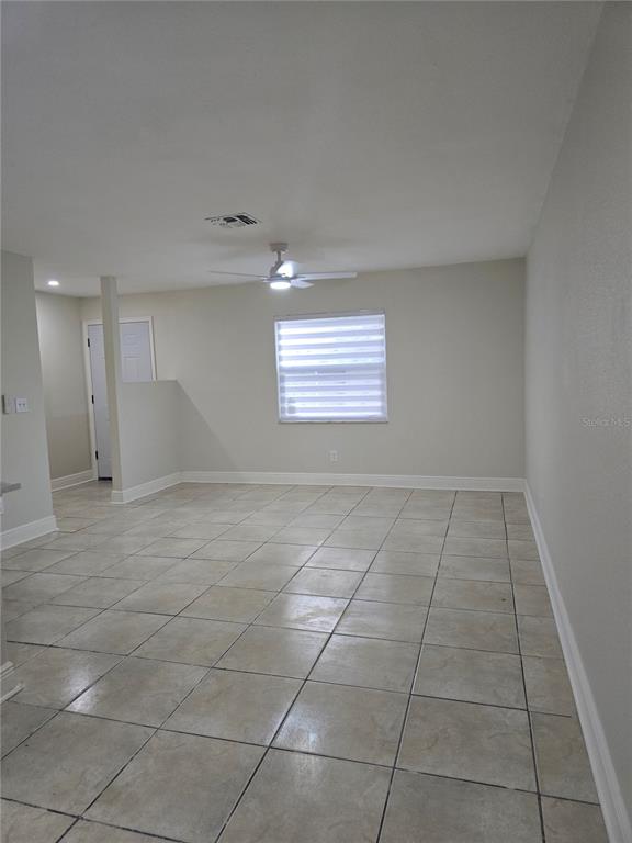 An empty room with light-colored tile flooring, a ceiling fan, and a window with blinds — 3064 SAINT PAUL DRIVE UNIT 3064, WINTER HAVEN, FL