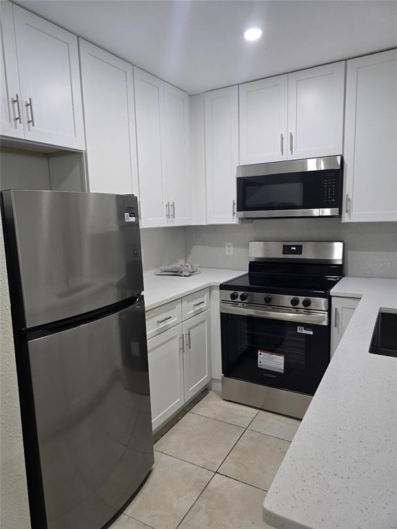 A kitchen features white cabinets, stainless steel appliances, and light-colored countertops — 3064 SAINT PAUL DRIVE UNIT 3064, WINTER HAVEN, FL