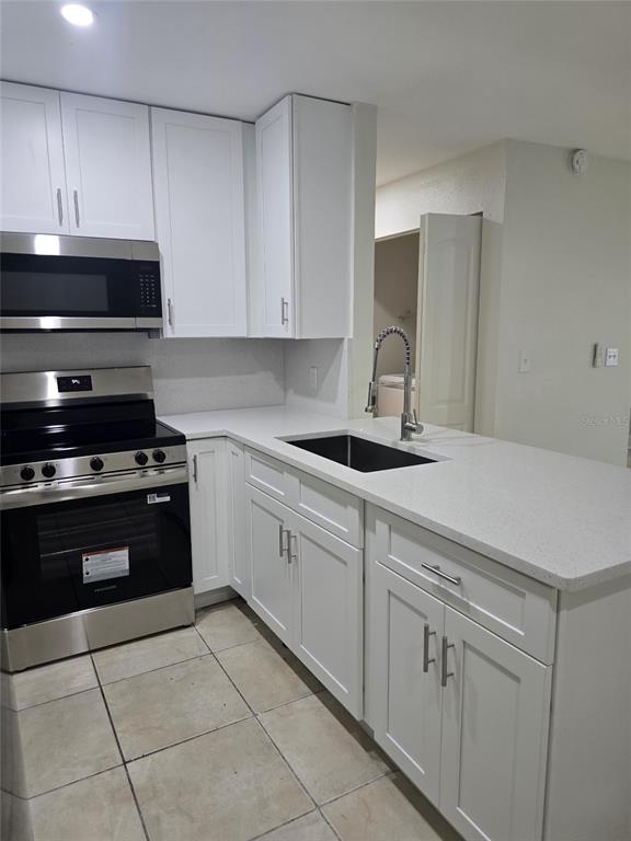 A kitchen features white cabinets, stainless steel appliances, and a white countertop with a sink — 3064 SAINT PAUL DRIVE UNIT 3064, WINTER HAVEN, FL