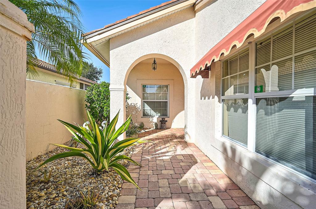 A paved walkway leads to a covered entryway with an arched opening and a window — 4041 MURFIELD DRIVE E, BRADENTON, FL