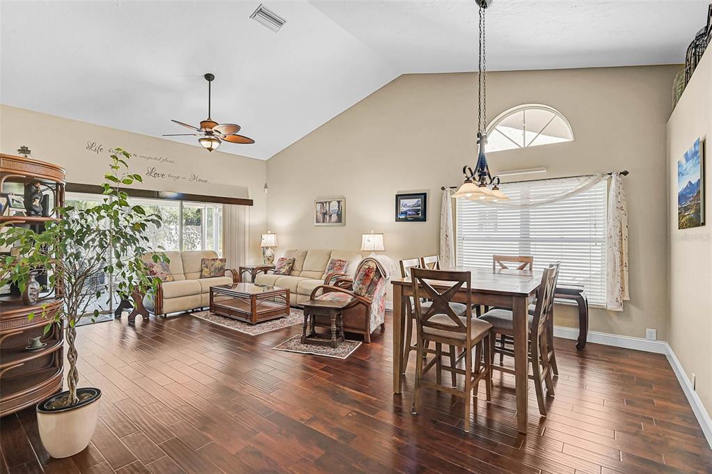 A living and dining area with vaulted ceilings, dark wood floors, and a ceiling fan — 4041 MURFIELD DRIVE E, BRADENTON, FL