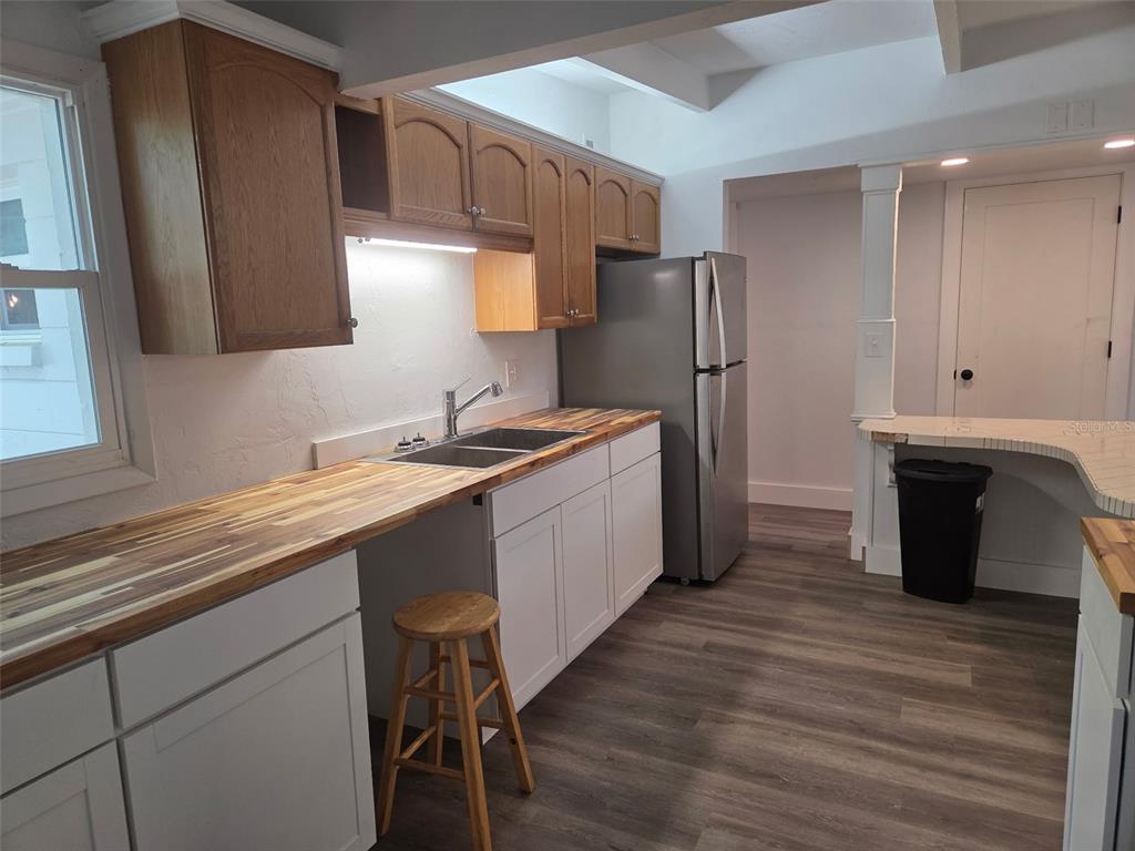 A kitchen features white lower cabinets, wood upper cabinets, butcher block countertops, and stainless steel appliances — 2839 NE 10TH DRIVE, GAINESVILLE, FL