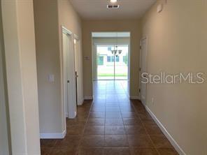 A tiled hallway leads from the entrance toward a bright living area with sliding glass doors — 15607 PORTER ROAD, WINTER GARDEN, FL