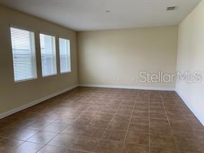 An empty room features tan tile flooring, light-colored walls, and three windows with white blinds — 15607 PORTER ROAD, WINTER GARDEN, FL
