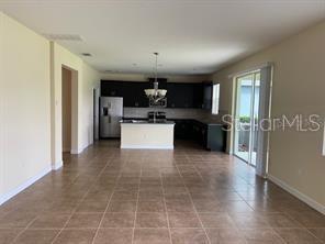 An open-concept kitchen with dark cabinets and a center island overlooks a tiled living area — 15607 PORTER ROAD, WINTER GARDEN, FL