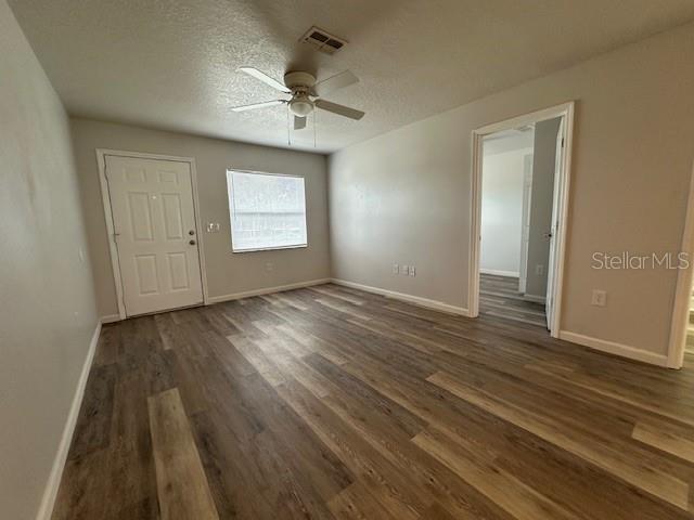 An empty room features light gray walls, wood-look flooring, a ceiling fan, and two doorways — 2781 LANDOVER BOULEVARD, SPRING HILL, FL