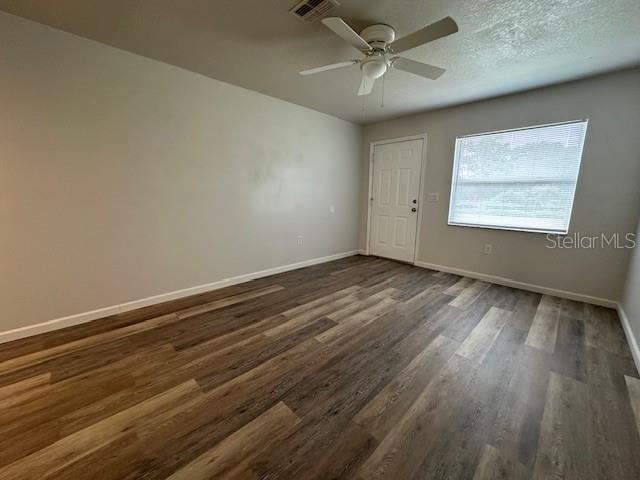 An empty room features wood-look flooring, a ceiling fan, a white door, and a window — 2781 LANDOVER BOULEVARD, SPRING HILL, FL