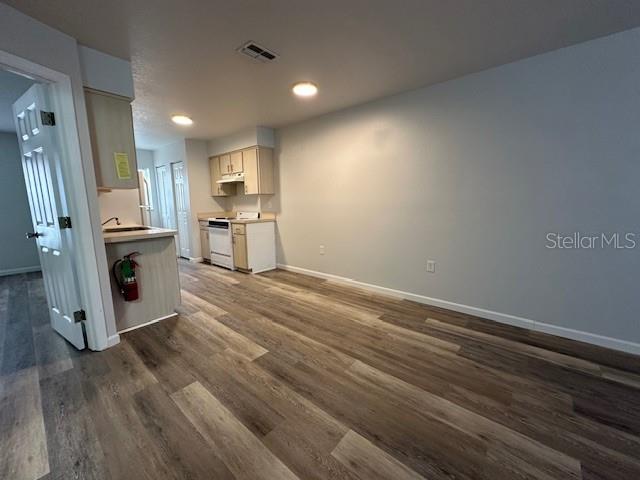 A kitchen with light wood cabinets and wood-look flooring opens into a living area — 2781 LANDOVER BOULEVARD, SPRING HILL, FL