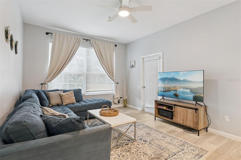 A living room features a blue sectional sofa, a white coffee table, and a television console — 8107 COCONUT PALM WAY UNIT 205, KISSIMMEE, FL
