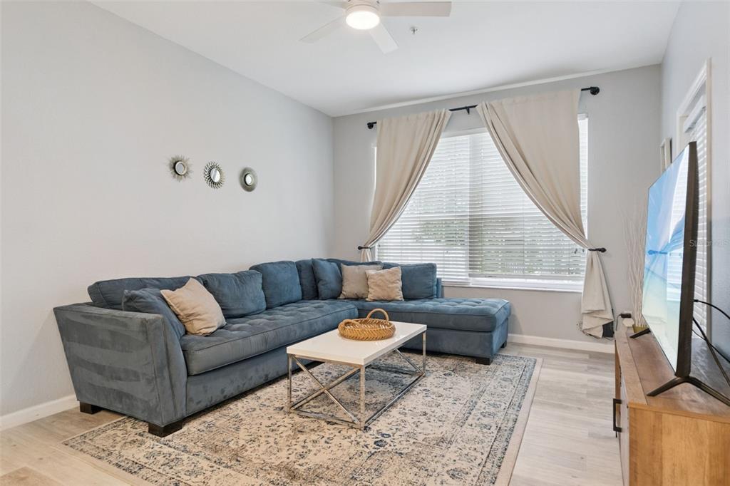 A living room features a blue sectional sofa, white coffee table, and a large window — 8107 COCONUT PALM WAY UNIT 205, KISSIMMEE, FL