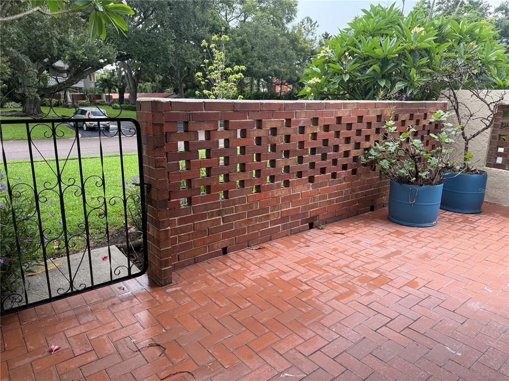A brick patio features a decorative open-work brick wall and a black metal gate — 1012 PEARCE DRIVE UNIT 111, CLEARWATER, FL