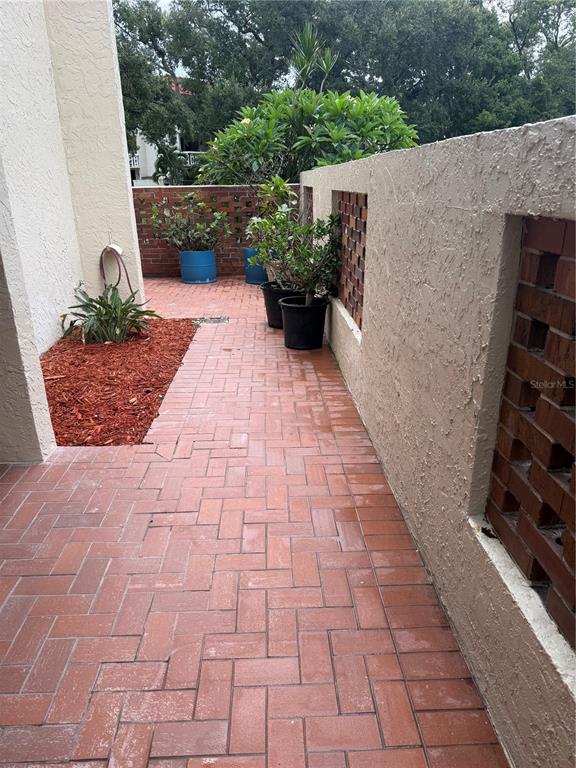 A patio with a brick floor, a small table with two chairs, and potted flowers — 1012 PEARCE DRIVE UNIT 111, CLEARWATER, FL