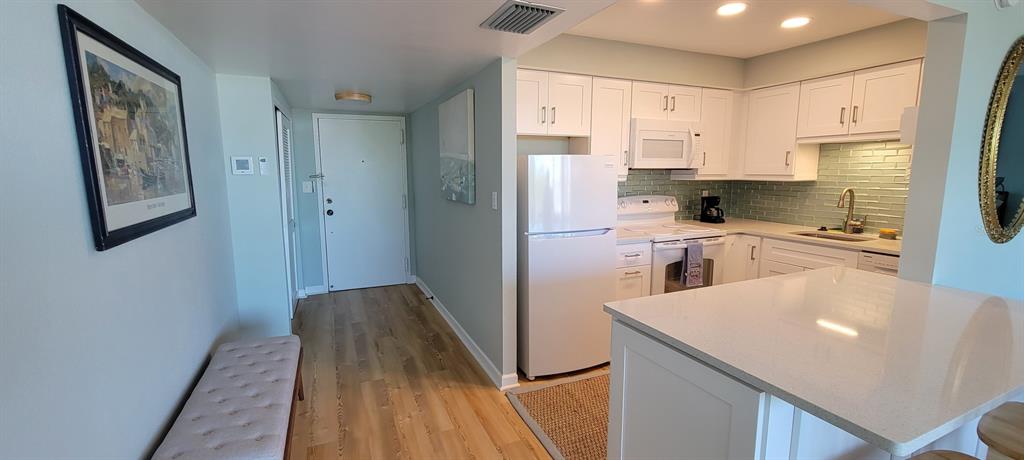 A kitchen with white cabinets, stainless steel appliances, and a quartz-topped island — 632 EDGEWATER DRIVE UNIT 537, DUNEDIN, FL