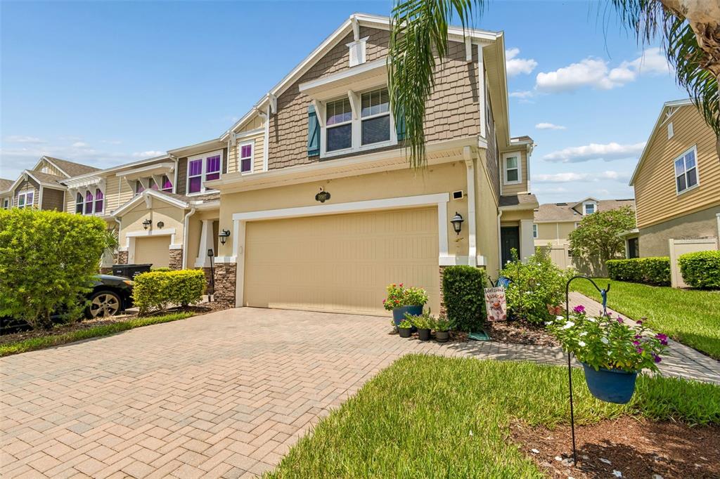 A two-story townhouse with a beige stucco facade, shingled gable, and a paved driveway — 18907 CORNUTA STREET, LUTZ, FL