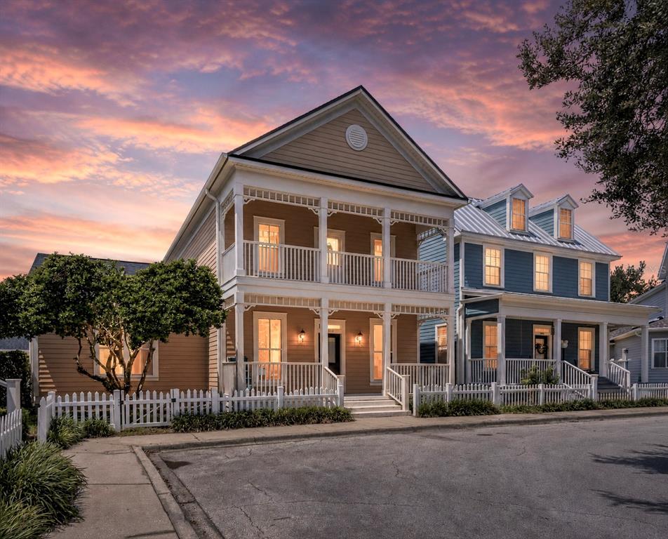A two-story yellow house with a double-decker porch stands next to a blue house — 1010 PERIWINKLE COURT, CELEBRATION, FL