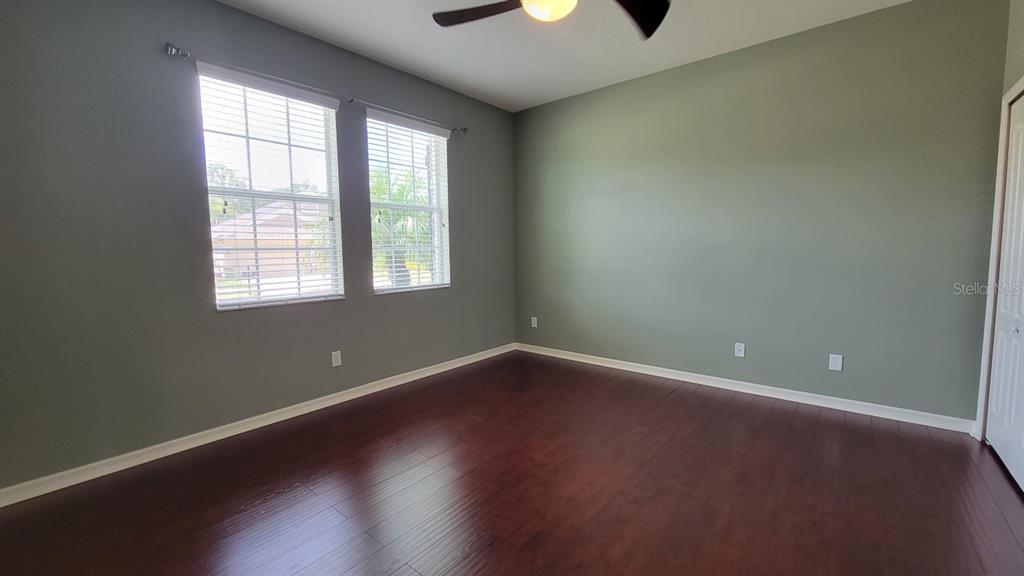 An empty room features dark wood flooring, sage green walls, and two windows with blinds — 2229 VALTERRA VISTA WAY, VALRICO, FL